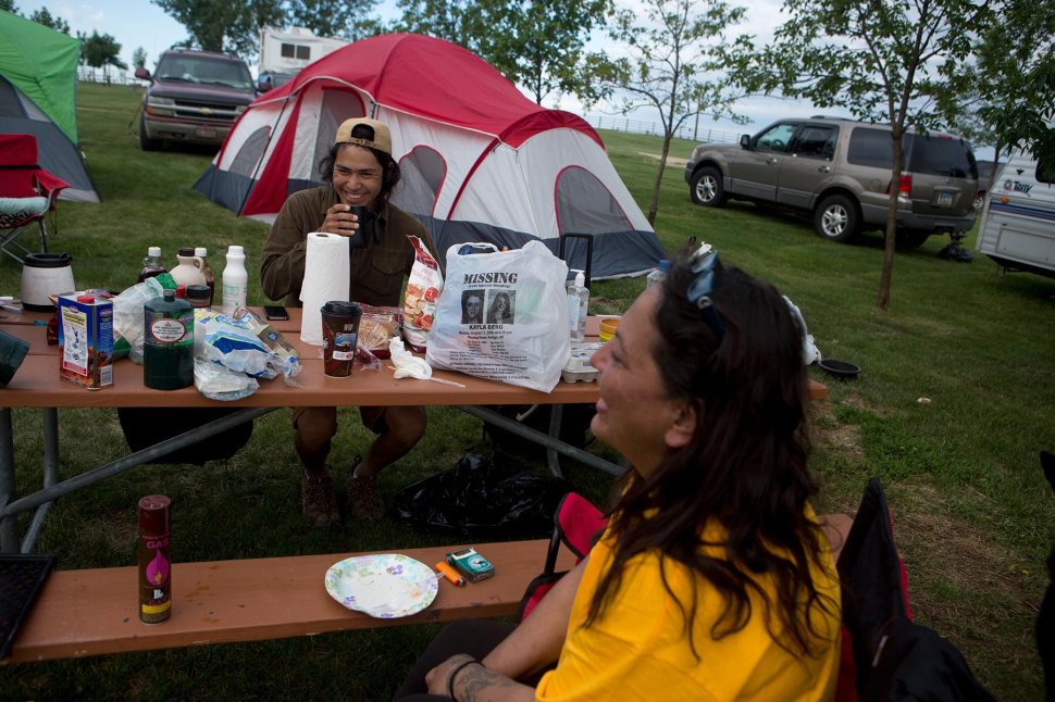 In this June 13, 2015 photo, Kalen Goodluck, left, and Lissa Yellowbird-Chase visit over morning coffee in their last few hours at the campsite before packing up and heading home after a weekend of searching for any signs of a body. © Kristina Barker